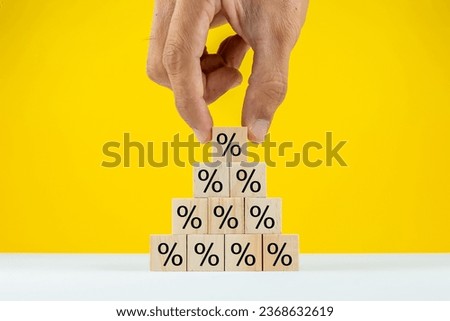 Hands Stacking Percentage Signs on Wood Toy Block