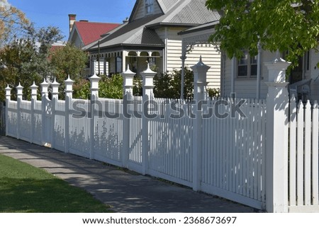 CHARACTER STYLE TIMBER RESIDENTIAL PICKET FENCE AND GATE An impressive decorative white wooden fencing with solid posts, ornate cap finials, decorative detailed top trims in a street of period homes Royalty-Free Stock Photo #2368673697