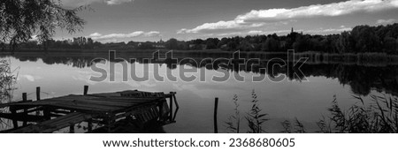 Black and white picture of the landscape.Rural landscape near a pond. Quiet lake and reflections in it. Autumn mood near a pond. Panorama of an autumn landscape in the countryside.