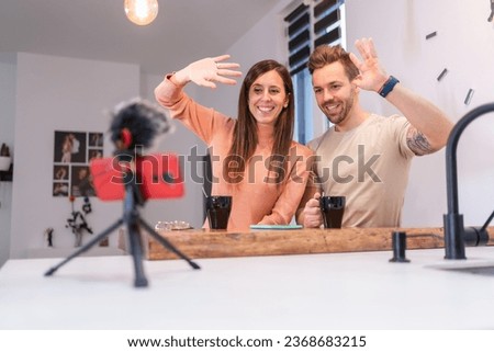 Focus on a young couple waving while vlogging at home