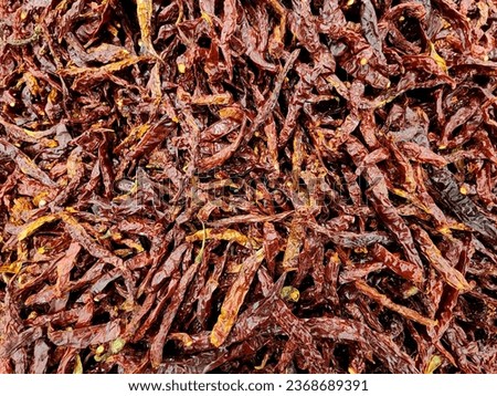 The picture shows a pile of fresh dried chilies on the table. Picture in horizontal format.