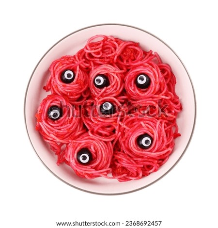 Red pasta with decorative eyes and olives in bowl isolated on white, top view. Halloween food
