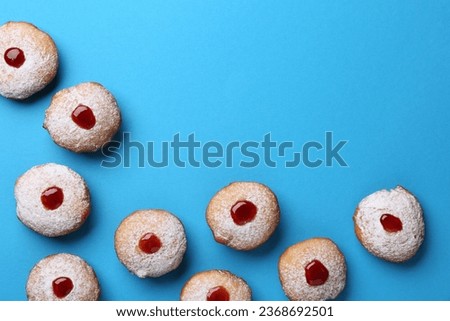 Hanukkah donuts with jelly and powdered sugar on turquoise background, flat lay. Space for text