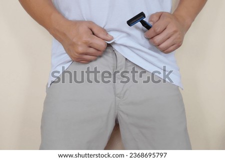 Closeup of male crotch with hand holding a shaver. Shave pubic hair down under concept. Men's Fitness, grooming and health. Royalty-Free Stock Photo #2368695797