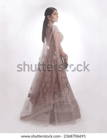 This photograph showcases a stunning Indian bride adorned in traditional attire, radiating grace and elegance while posing for a picture. The bride's ensemble includes ornate jewelry, makeup, 