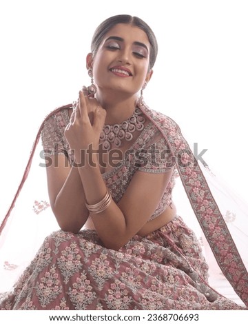 This photograph showcases a stunning Indian bride adorned in traditional attire, radiating grace and elegance while posing for a picture. The bride's ensemble includes ornate jewelry, makeup, 