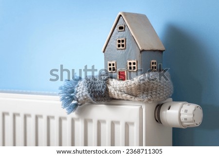 House model wrapped in scarf on radiator home winter heating and insulation background fuel and energy crisis concept Royalty-Free Stock Photo #2368711305