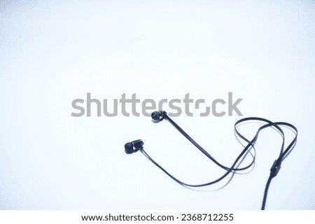 black plastic earphone with gold ring on sonic blue background 