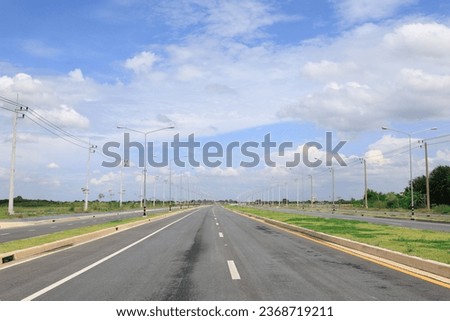 Asphalt highway road with concrete walkway with wide blue sky background.