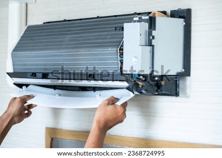 Selective focus to cooling coil panel of air conditioner with blurry technician is assembling an air conditioner after cleaning it.