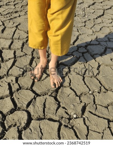 A child's feet stand on dry land, global warming and climate change impact children's development and future. Royalty-Free Stock Photo #2368742519