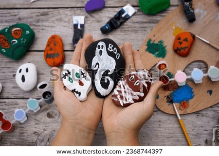Close-up of children's hands holding stones painted with acrylic paints for the Halloween holiday