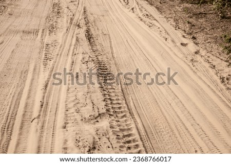 Selective blur on a tire track on a sand, traces of tyres and wheels of cars and vehicles driving off road on a dirt path, a sandy trail on a beach or a desert. Royalty-Free Stock Photo #2368766017