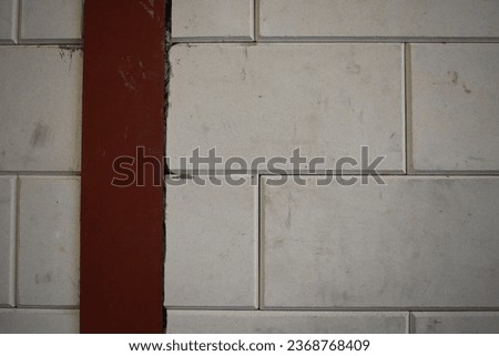Wall made of white cinder blocks, and a vertical red support beam