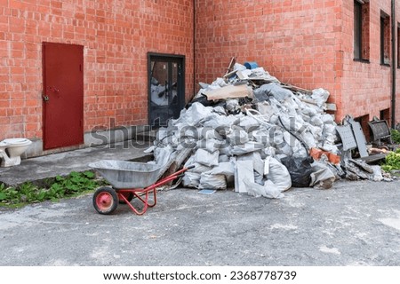 A large pile of construction debris after repair lies near a brick building Royalty-Free Stock Photo #2368778739