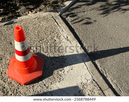 Red plastic cone on the road. A traffic cone warns of danger