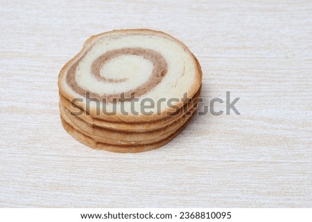 Several slices of round bread with chocolate swirls in the middle.
Selected focus, indoors and additional light.