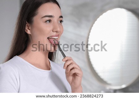 Happy woman brushing her tongue with cleaner in bathroom, space for text Royalty-Free Stock Photo #2368824273