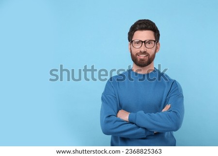 Portrait of handsome man in glasses on light blue background, space for text