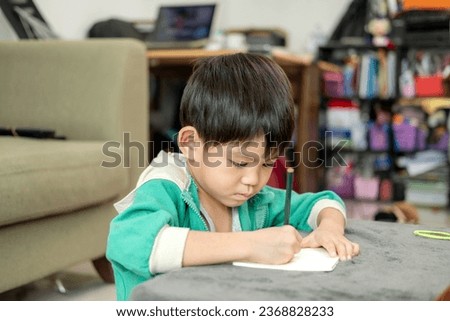 A boy is drawing pictures on a notebook on the table. Learning outside the classroom