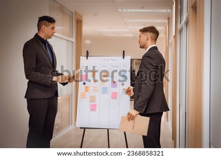 Team of business people using whiteboard sheets showing graphs, infographics. Discussing with colleagues, meeting presentation, professional project manager, group negotiating in office.