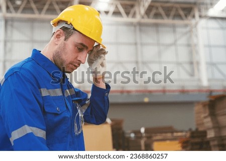 Tired male engineer worker working in factory in break time. Male worker working and wearing safety uniform, helmet in industry factory Royalty-Free Stock Photo #2368860257