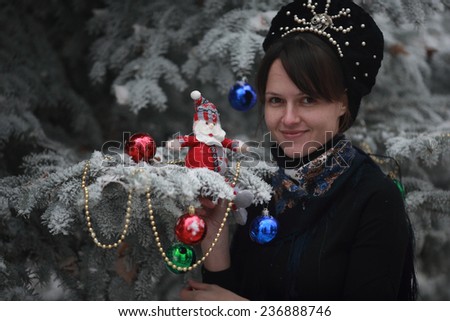 elegant girl standing next to a Christmas tree decorated with toys