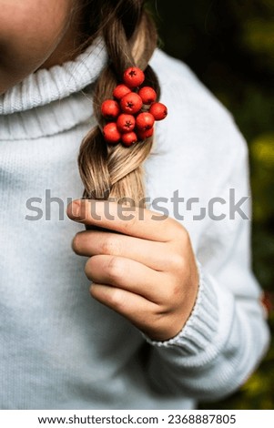 a girl in a white sweater with a rowan in her hair