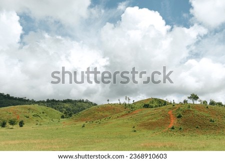 Green small hills with cloudy sky countryside scenery in Thailand.