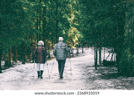old elderly couple retired spouses walk in the park. elderly couple are doing scandinavian walk. Royalty-Free Stock Photo #2368935019