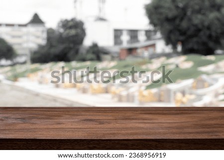 Empty wooden desk with blurred background of tomb and graveyard.