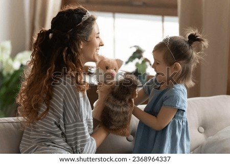 Loving happy young mom and cute little preschooler daughter have fun engaged in activity with toys, overjoyed millennial mother or nanny play puppet theater together with excited small girl child