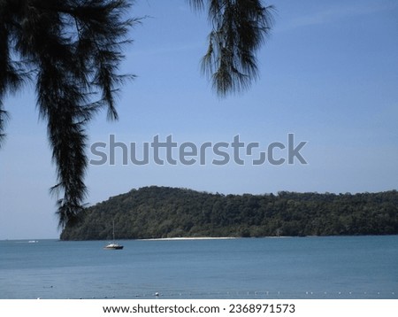 sailboat anchored in calm seas between an island and the shore