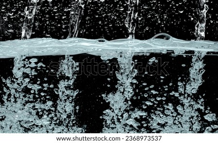 Drinking water pouring into clear glass. Bubbles inside from pouring falling clear water. Drinking soda water flush air bubble. Black background isolated freeze element