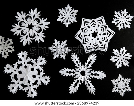 Set of snowflakes cut out of white paper on a black background. Handmade new year and Christmas decoration