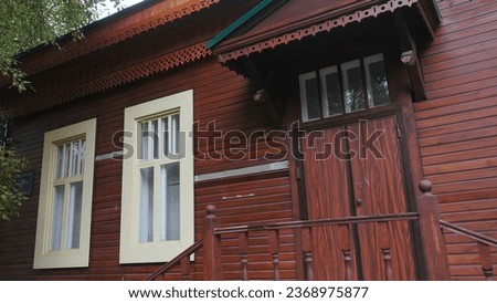 Old wooden house in summer. Stock footage. Staircase with entrance to old wooden house. Beautiful facade of old house made of red wooden beams