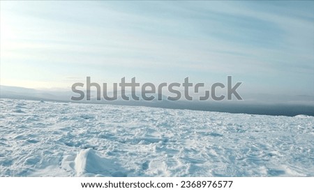 Beautiful winter view of plateau and mountains on horizon. Clip. Snowy plain on top of plateau on sunny winter day. Beautiful landscape of winter mountains and hills in sunny weather Royalty-Free Stock Photo #2368976577