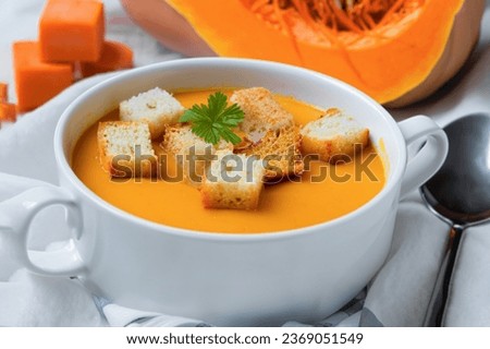Composition with pot of tasty pumpkin cream soup and autumn leaves on wooden background