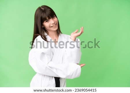 Little Caucasian girl doing karate over isolated background extending hands to the side for inviting to come