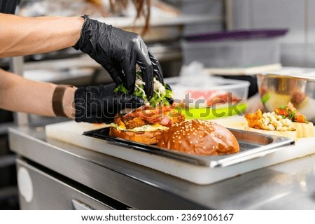 chef hand cooking cheeseburger with vegetables and meat on restaurant kitchen