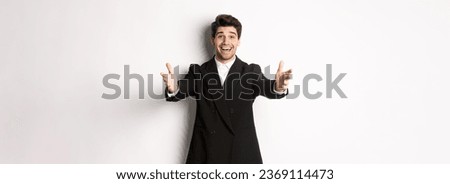 Portrait of happy attractive man in suit, hosting a party, reaching hands forward to greet you, want to hold something or hug, standing over white background.