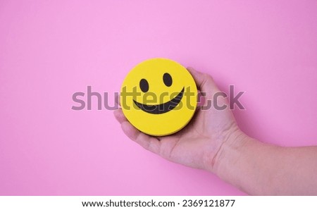Yellow funny face in a woman's hand. Social concept of friendly communication.