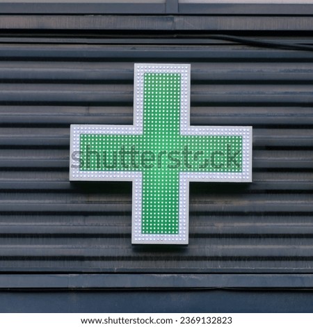 Green cross pharmacy signs on the wall of a city house