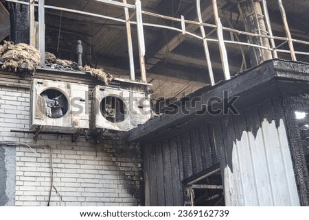 Building was damaged by fire. Burnt facade of building. Air-conditioned building was destroyed by fire. Concept - fire in house due to electrical equipment. Brick house destroyed by flame Royalty-Free Stock Photo #2369162739
