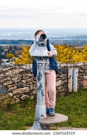 A girl looking through panoramic binoculars Royalty-Free Stock Photo #2369165519