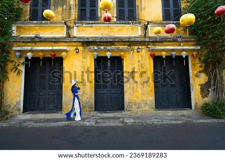 Vietnamese girls in national costumes Walk and lead an ancient bicycle. Play the old town of Hoi An, Vietnam. with a beautiful and unique architecture. Royalty-Free Stock Photo #2369189283
