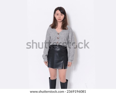 attractive asian young woman wearing gray sweater with black skirt posing in studio