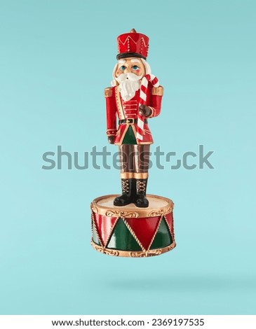 Christmas card. Falling in the air Christmas bauble in the shape of nutcracker isolated on blue background. Christmas figurine. Levitation or zero gravity conception. High resolution image. Royalty-Free Stock Photo #2369197535