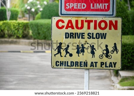 Sign caution speed limit drive slow children at play on yellow background at park in evening sunset, playground sign,landscape garden background.