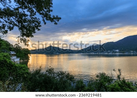 Sunset over calm water in coastal bay by coastal village and mountains